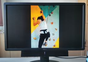 Monitor mit dem Bild einer Frau, die gesichert an einer Kletterwand klettert