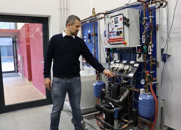 An einem Lehrstand zeigt Prof. Dr. Rath, wie die Studierenden lernen erneuerbare Energiesysteme wie Wärmepumpen in Gebäudesysteme zu integrieren.