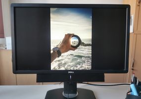 Auf einem Monitor ist das Bild einer Hand mit einer Linse, die das Bild einer Insel klar zeigt