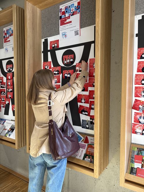 Mädchen hängt ein Bild auf eine Pinnwand