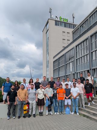 Eine Gruppe Studierender vor einem Gebäude aus Glas und Beton
