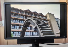 Monitor auf dem das große Zahnrad vor der Hochschule Bochum zu sehen ist