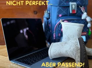 Laptop mit Kinder-Gummistiefel und einem Kinder-Rucksack