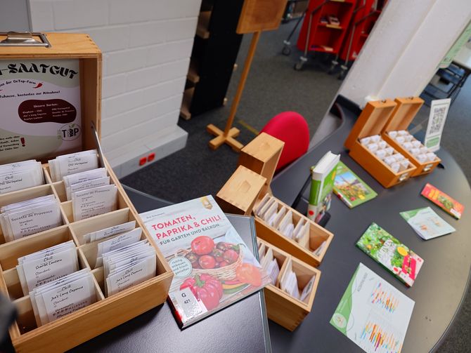 Blick auf die Saatgutbibliothek im Eingangsbereich der Fachbibliothek Technik mit den Saatgutkästen, passenden Büchern und Deko