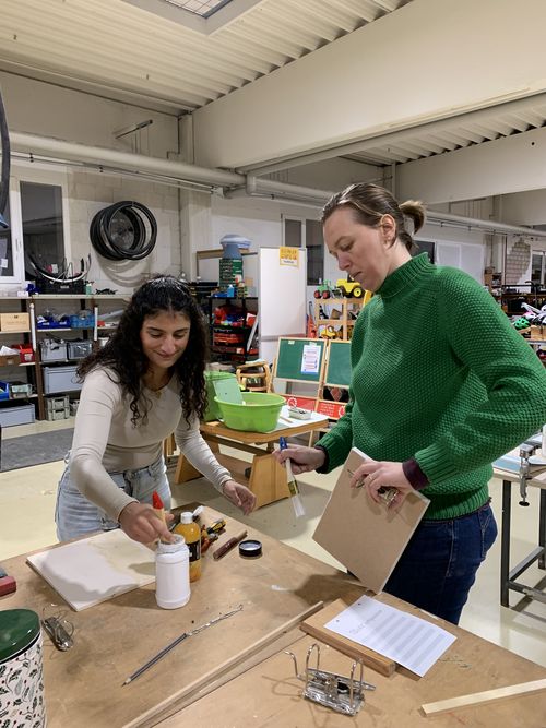 Foto vom Upcycling Workshop. 4 Teilnehmerinnen stehen um einen Werktisch und arbeiten an ihren Produkten. Beide Pinseln ihre Bretter an