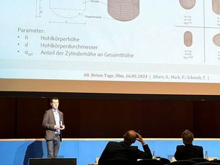 Vortragender vor einer Projektion mit technischen Zeichnungen