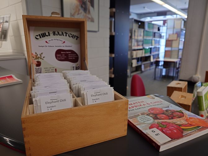 Blick auf die Saatgutbibliothek im Eingangsbereich der Fachbibliothek Technik mit den Saatgutkästen, passenden Büchern und Deko