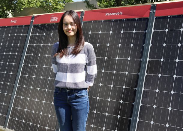 Studentin Phuong Thao Dang steht vor einer Photovoltaikanlage.