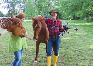 Prof. Dr. Dietmar Gerhardt steht mit Sonja Podjawerschek und zwei Pferden auf der Wiese. In der Hand hält er eine Drohne.
