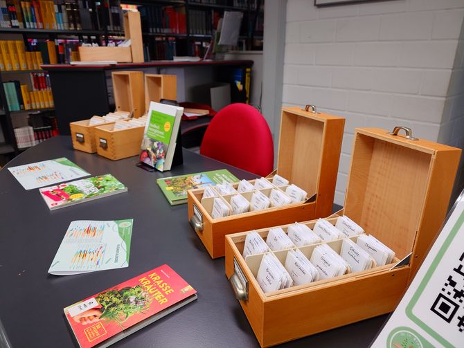 Blick auf die Saatgutbibliothek im Eingangsbereich der Fachbibliothek Technik mit den Saatgutkästen, passenden Büchern und Deko