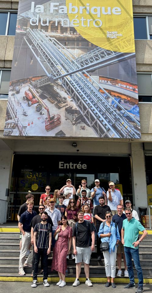 Studierende stehen auf einer Treppe vor einem bunten Gebäude