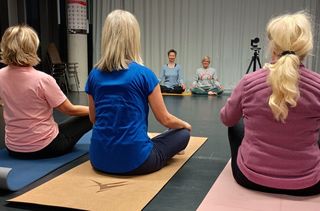Rückenansicht von Frauen in Sportkleidung im Schneidersitz