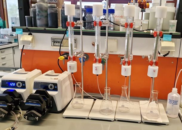 Das Bild zeigt Kleinsäulentests im Labor für Siedlungswissenschaft, mit denen Dr. Luca Marco Ofiera unter anderem die Schadstoffaufnahme unterschiedlicher Arten von Aktivkohle und natürlichem Zeolith erprobte.