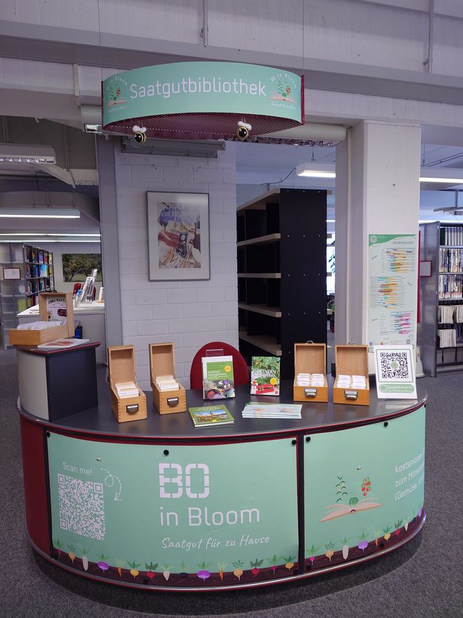 Blick auf die Saatgutbibliothek im Eingangsbereich der Fachbibliothek Technik mit den Saatgutkästen, passenden Büchern und Deko