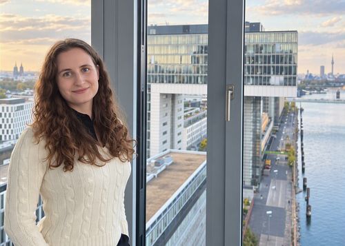 Dorothea Kretschmar hat den Masterstudiengang ‚Accounting, Auditing and Taxation‘ absolviert und arbeitet heute als Wirtschaftsprüfer bei Forvis Mazars. Ein Portrait von MAAT-Alumna Dorothea Kretschmar aus einem Gebäude mit Aussicht auf den Rhein.