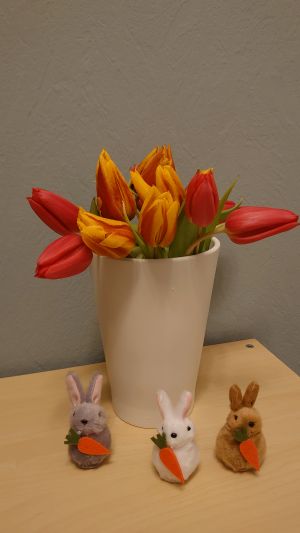 Eine Vase mit gelbroten Tulpen und Osterdekoration